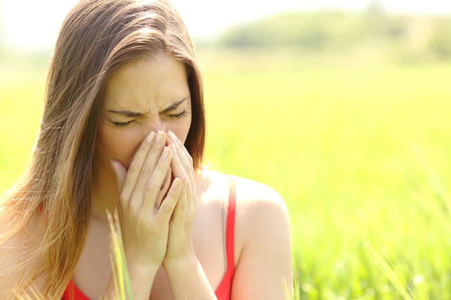 Woman in a field of flowers suffering from allergies