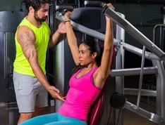 Woman working out at the gym with the help of a trainer