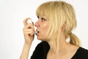 Asthmatic patient with an inhaler in her mouth