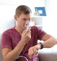 A man with a nebulizer to his nose. We offer natural asthma treatment