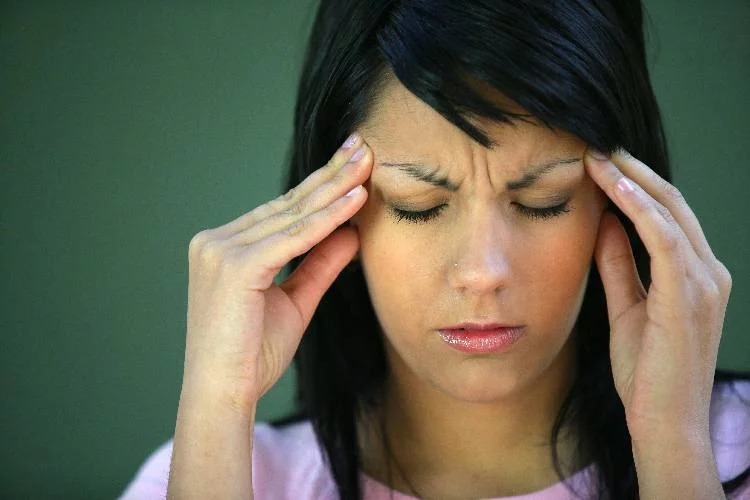 Woman grasping head with a lyme disease headaches showing what it feel like