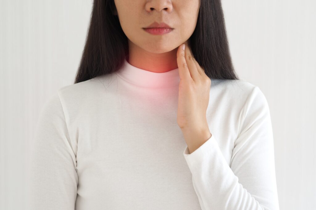 woman noticing her swollen lower neck - graves disease symptoms